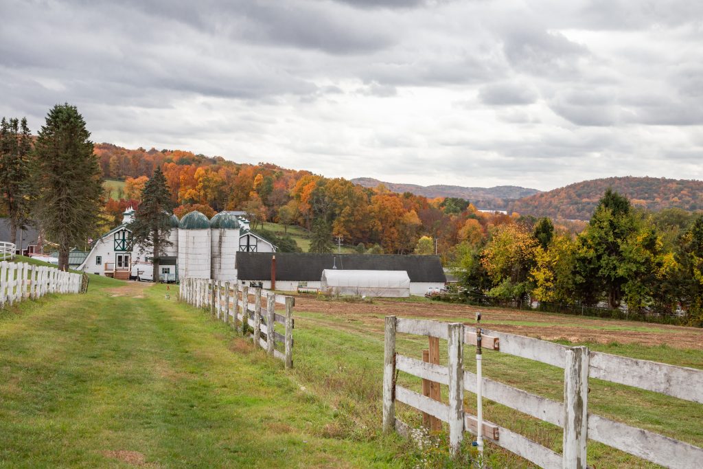 Rural farm with white fence, barns, and silos surrounded by rolling hills in Putnam County Indiana during fall
